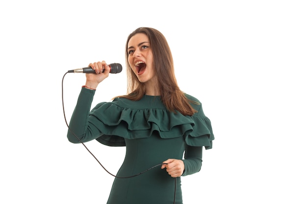 Mulher bonita canta no microfone um karaokê com vestido verde isolado no fundo branco