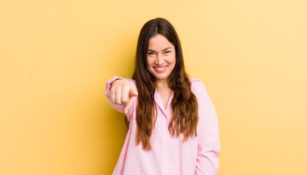 Foto mulher bonita caucasiana apontando para a câmera com um sorriso amigável confiante e satisfeito escolhendo você