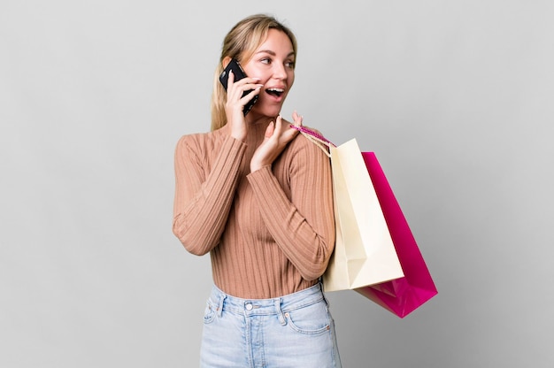 Mulher bonita caucasiana com sacolas de compras e um smartphone