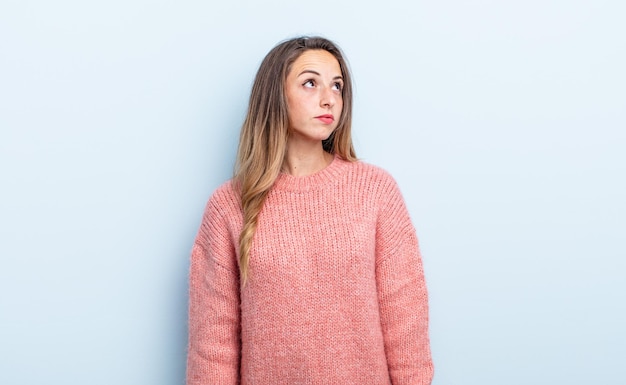 Mulher bonita caucasiana com uma expressão preocupada, confusa e sem noção, olhando para copiar o espaço, duvidando