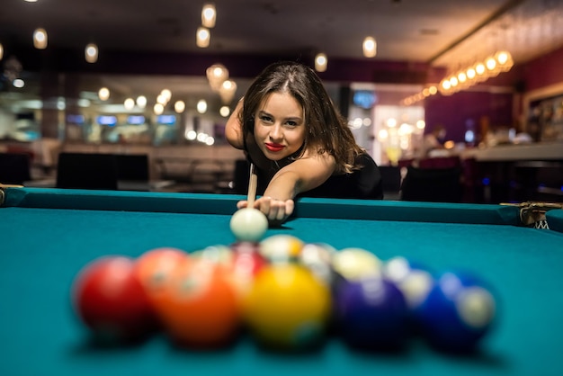 Mulher bonita no bar ao lado da mesa de sinuca, gente jogando