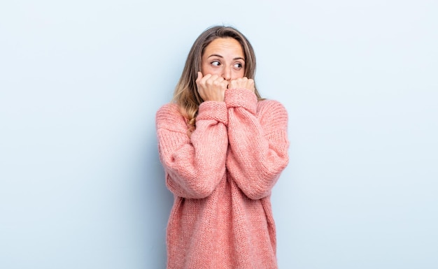 Mulher bonita caucasiana parecendo preocupada, ansiosa, estressada e com medo, roendo unhas e olhando para o espaço lateral da cópia