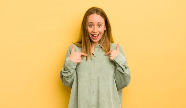 Mulher bonita caucasiana se sentindo feliz, surpresa e orgulhosa apontando para si mesma com um olhar espantado animado