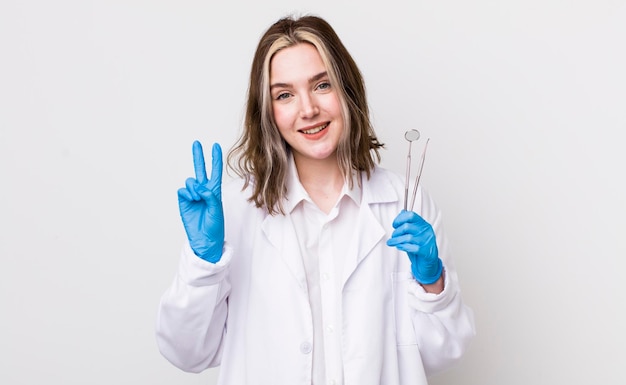 Mulher bonita caucasiana sorrindo e parecendo amigável mostrando o conceito de dentista número dois