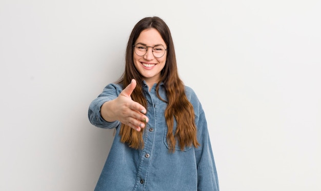 Mulher bonita caucasiana sorrindo feliz confiante e amigável oferecendo um aperto de mão para fechar um acordo cooperando