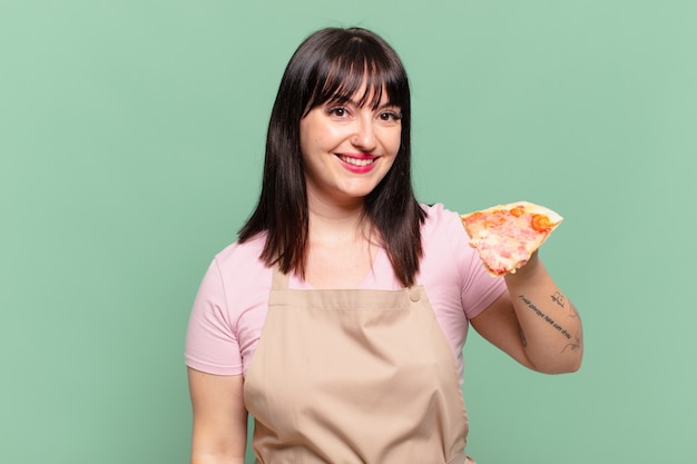Mulher bonita chef com expressão feliz e segurando uma pizza