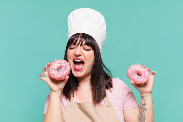 Mulher bonita chef com uma expressão feliz e rosquinhas segurando