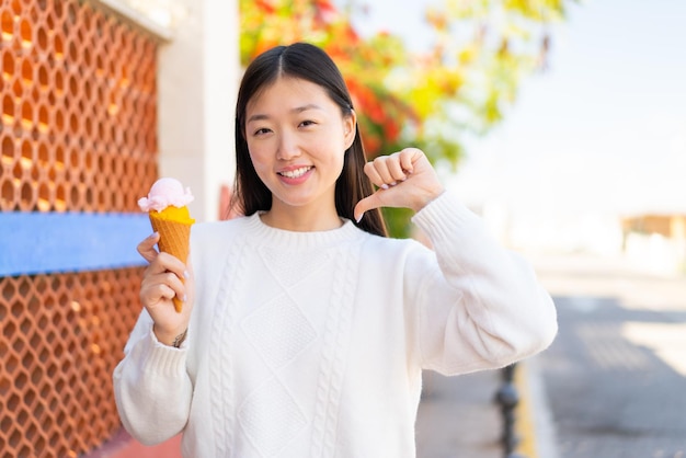 Mulher bonita chinesa com um sorvete de corneta ao ar livre orgulhoso e satisfeito