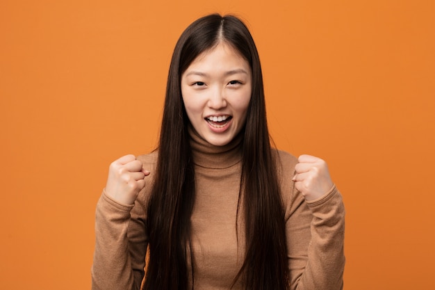 Mulher bonita chinesa jovem torcendo despreocupado e animado.