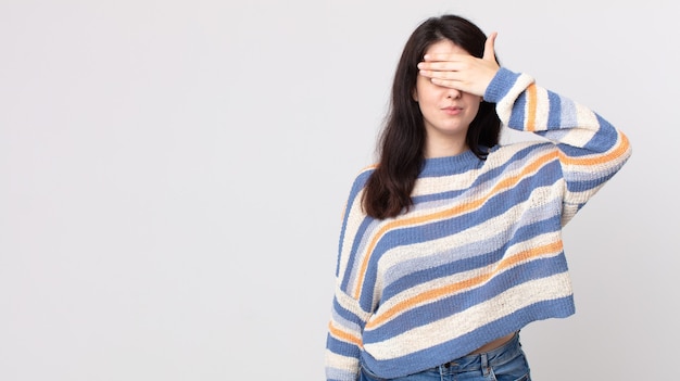 Mulher bonita cobrindo os olhos com uma mão, sentindo-se assustada ou ansiosa, imaginando ou esperando cegamente por uma surpresa