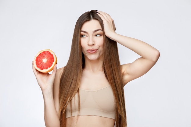 Mulher bonita com a pele limpa, fresca, segurando a toranja