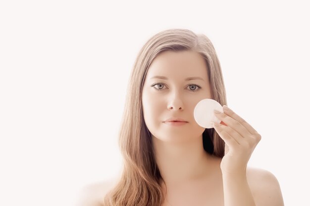 Mulher bonita com almofada de algodão, pele perfeita e cabelo brilhante como maquiagem, conceito de saúde e bem-estar, rosto de uma jovem modelo feminina para cosméticos para a pele e design de anúncio de beleza de luxo