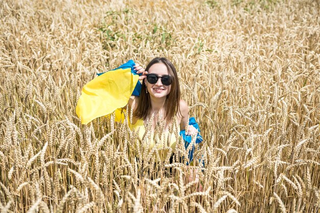 Mulher bonita com bandeira da ucrânia em fiel de trigo