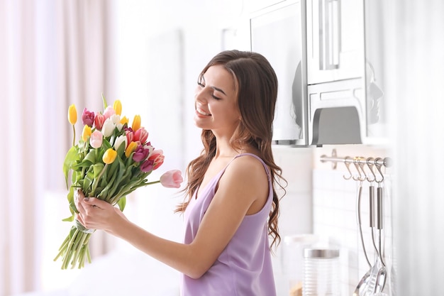 Mulher bonita com buquê de tulipas em casa