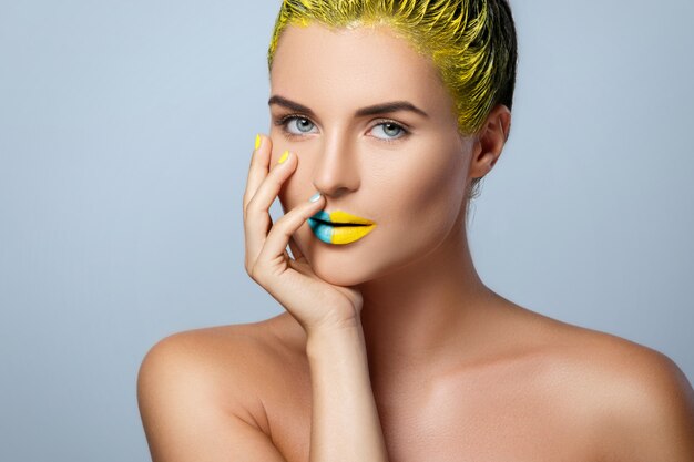 Mulher bonita com cabelo amarelo e unhas e lábios coloridos