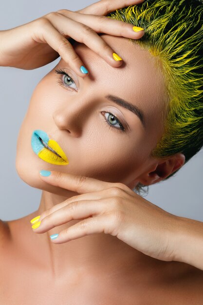 Mulher bonita com cabelo amarelo e unhas e lábios coloridos