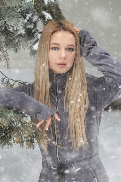 Mulher bonita com cabelo comprido posando na floresta com neve.