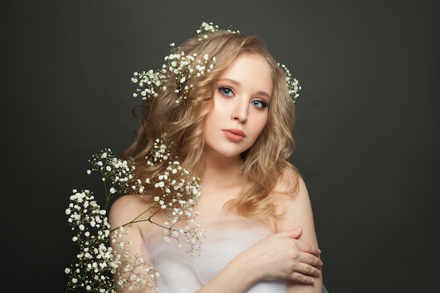 Mulher bonita com cabelo encaracolado longa e saudável e flores brancas