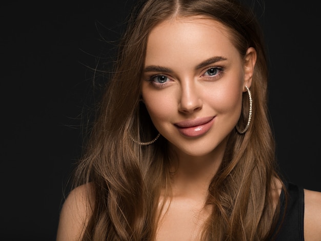 Mulher bonita com cabelo longo e saudável encaracolado morena brincos vestido preto fundo preto