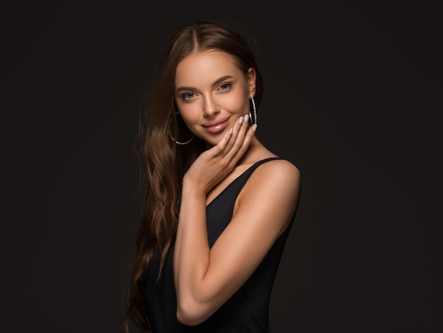 Foto mulher bonita com cabelo longo e saudável encaracolado morena brincos vestido preto fundo preto