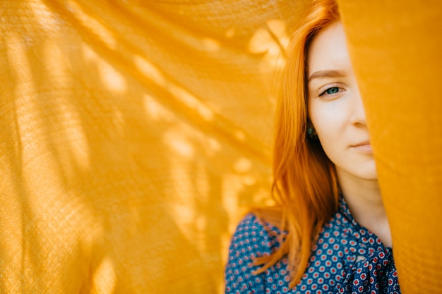 Mulher bonita com cabelo vermelho ao ar livre com véu laranja