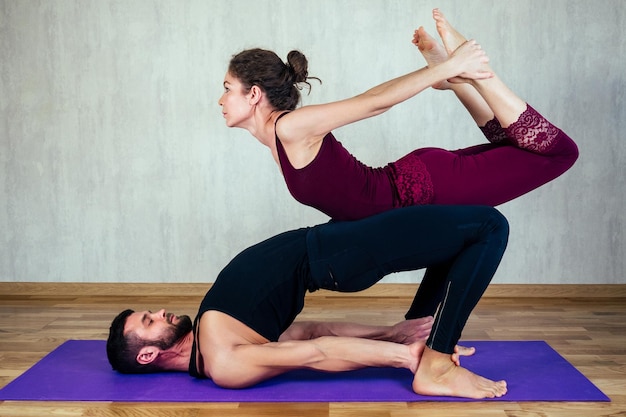 Mulher bonita com cabelos cacheados e um homem musculoso praticando ioga juntos no tapete de ioga conceito de ioga tântrica e amor casal apaixonado praticando ioga asan