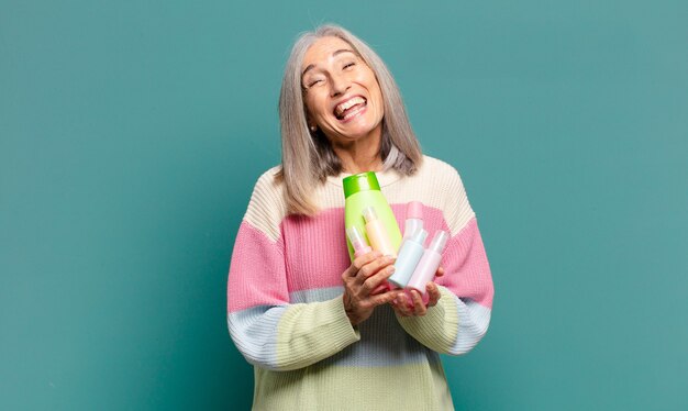 Mulher bonita com cabelos grisalhos e produtos para a pele