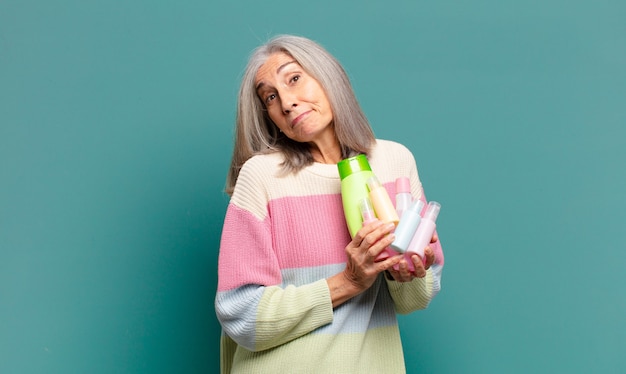 Mulher bonita com cabelos grisalhos e produtos para a pele