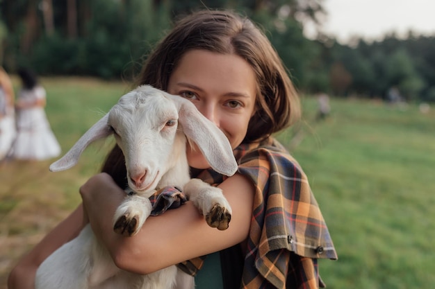 Mulher bonita com cabra pequena na zona rural tem amizade na natureza