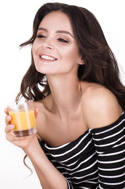 Mulher bonita com cachos de cabelo de pele saudável e suco de laranja posando no estúdio Rosto de beleza