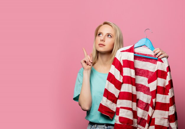 Mulher bonita com camisa em um cabide na parede rosa