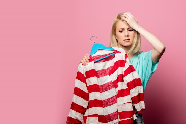 Mulher bonita com camisa em um cabide na parede rosa