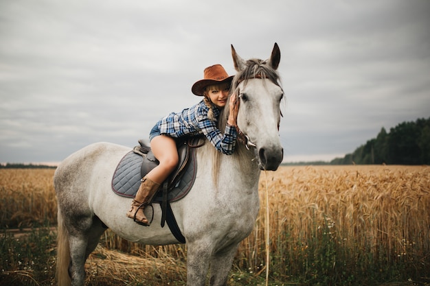 Mulher bonita com cavalo castanho no campo à noite