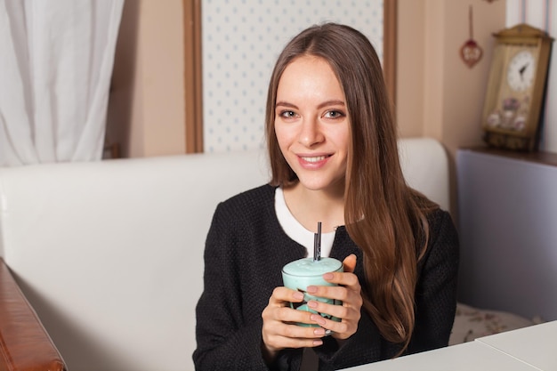 Mulher bonita com coquetel no café moderno