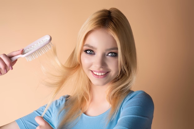 Mulher bonita com escova penteando o cabelo menina de beleza com cabelo liso isolado no fundo do estúdio