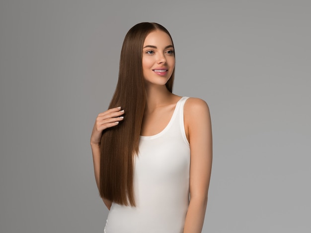 Mulher bonita com estilo casual natural de beleza de cabelo liso longa e saudável. Cor de fundo cinza