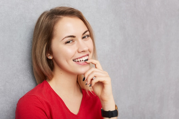 Mulher bonita com expressão feliz, sorri agradavelmente para a câmera