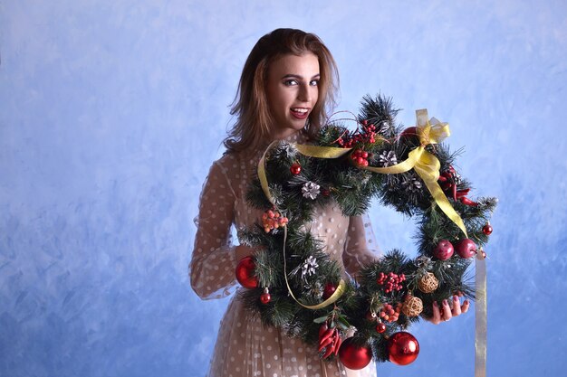 Mulher bonita com guirlanda de Natal nas mãos sobre fundo azul