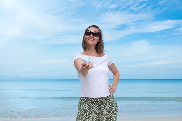 Mulher bonita com óculos de sol pretos segurando uma máscara médica