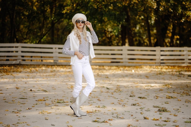 mulher bonita com óculos e uma boina branca no parque no outono