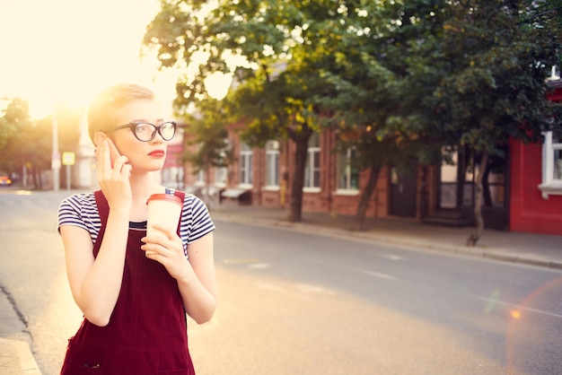 Mulher bonita com óculos na rua falando ao telefone no verão