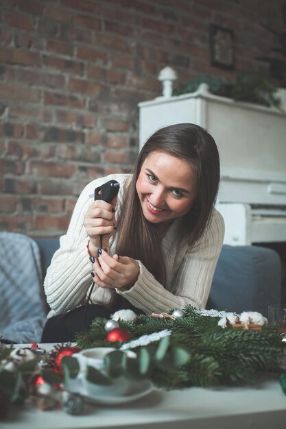 Mulher bonita com pistola de cola elétrica e decoração de natal, pessoas reais