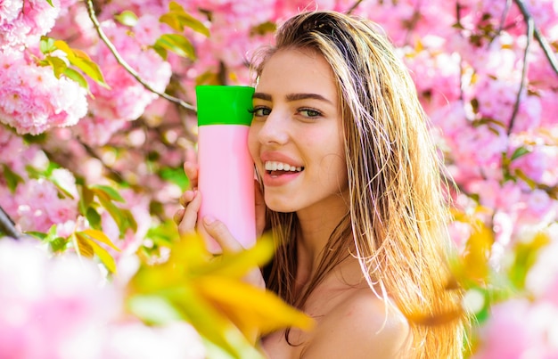 Mulher bonita com shampoo, bálsamo ou condicionador. Menina sorridente com cosméticos para cabelo.