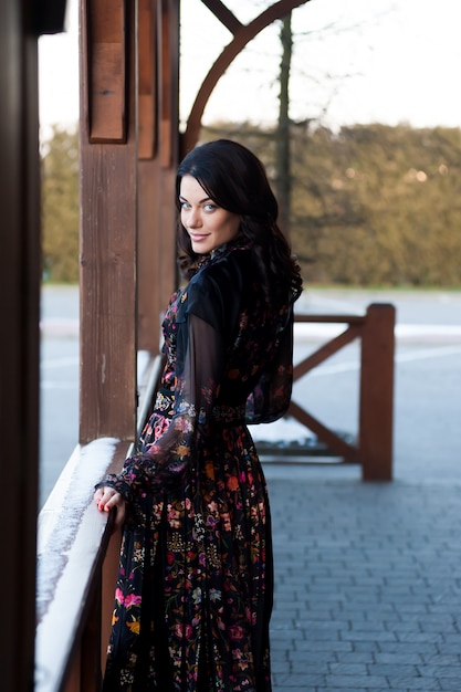 Mulher bonita com sorriso no vestido perto do corrimão de madeira