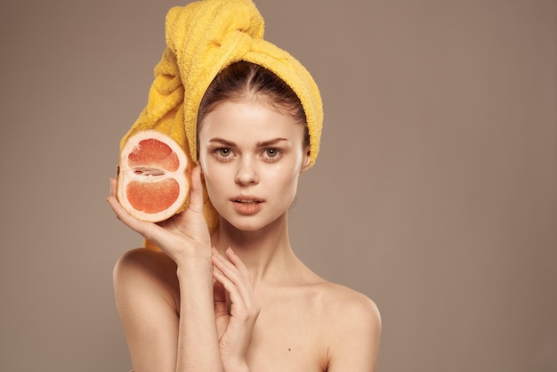 Mulher bonita com toalha na cabeça pele limpa ombros nus frutas cítricas nas mãos