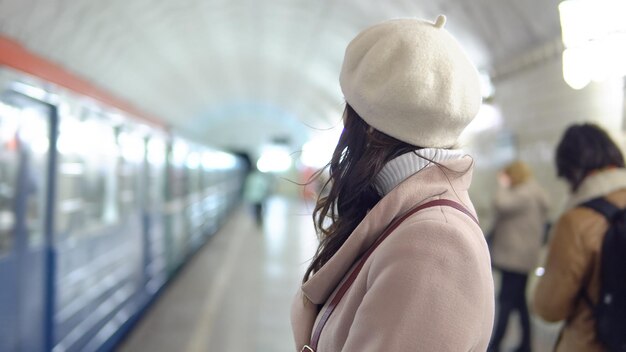 Mulher bonita com um casaco em metropiliten esperando um trem.