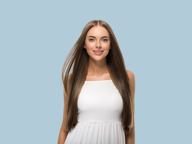 Mulher bonita com um lindo cabelo longo, liso e voador, vestido branco sobre um fundo de cor