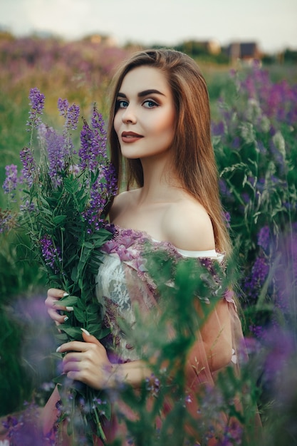 Mulher bonita com um vestido elegante posando com flores