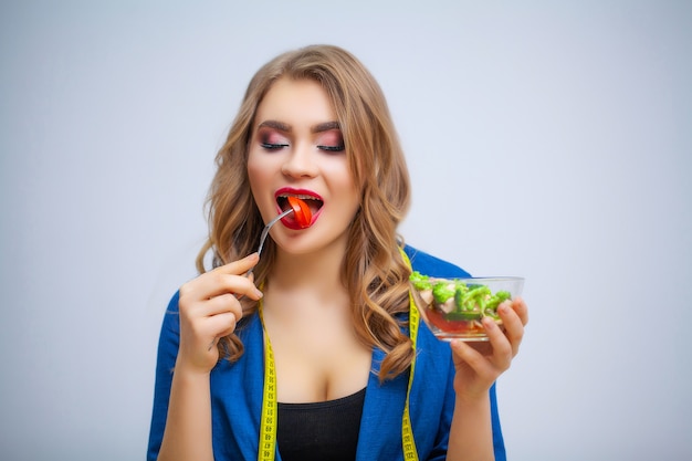 Mulher bonita come salada de legumes com muitas vitaminas