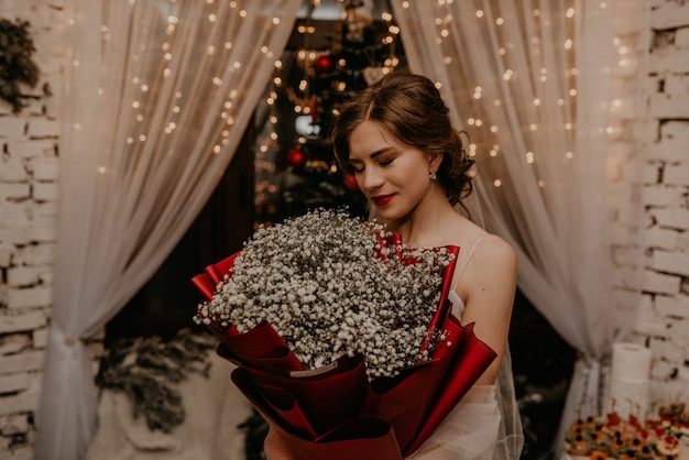 Foto mulher bonita comemorando ano novo e natal em uma árvore de natal decorada e guirlandas